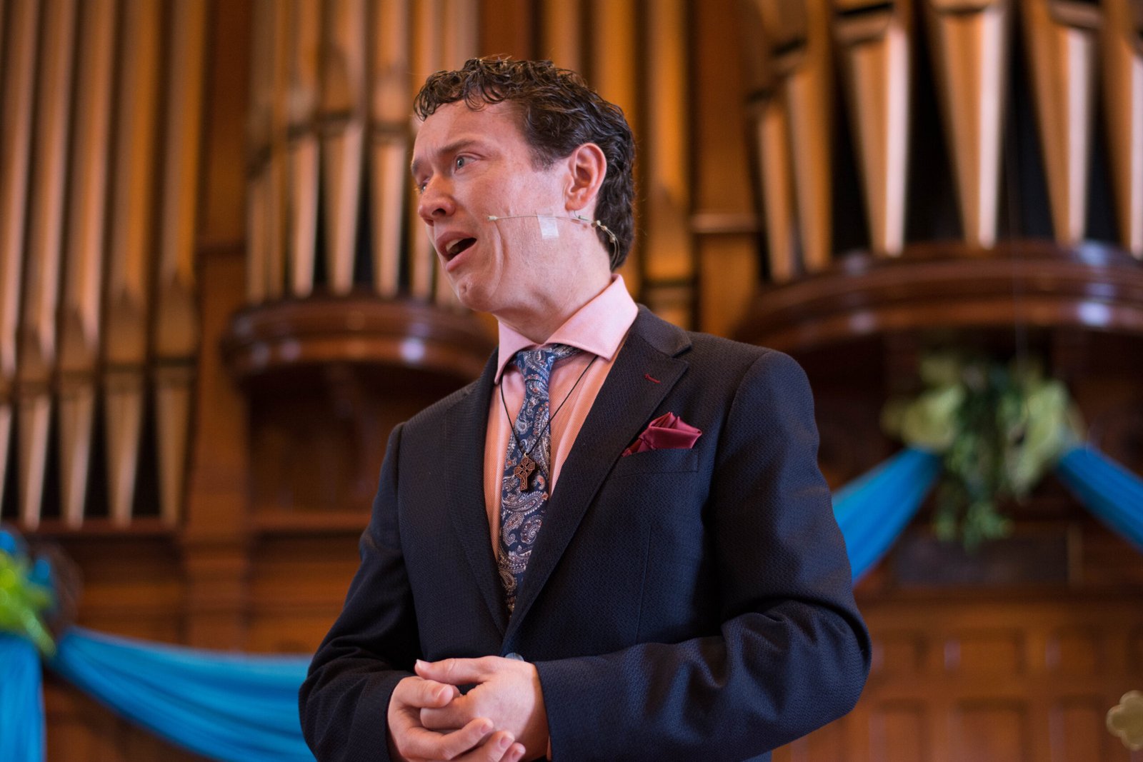Greg Simpson speaking in a church in front of organ pipes