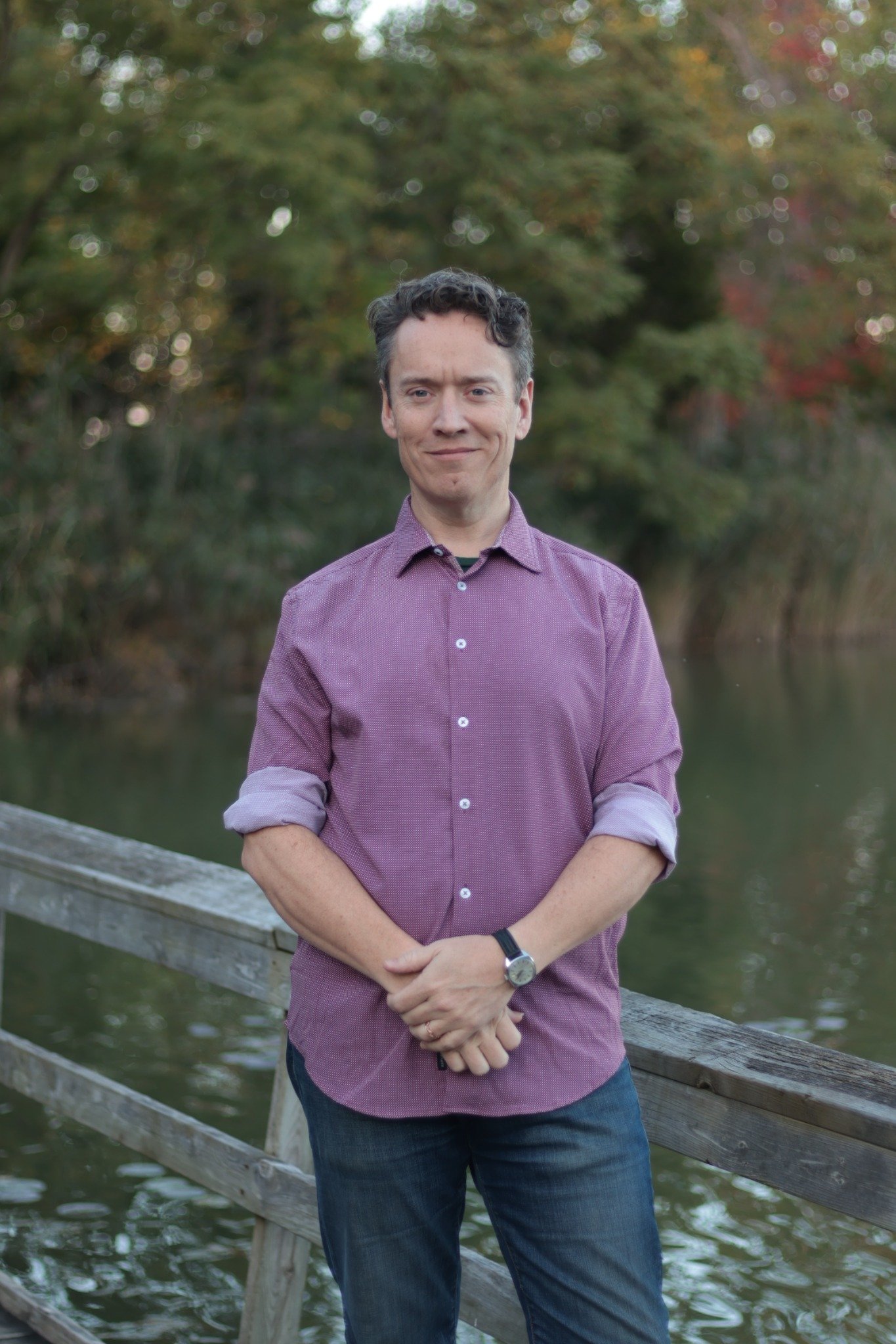 Greg Simpson standing beside a pond in a purple shirt